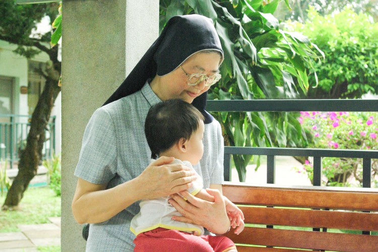 修女抱嬰兒側面照